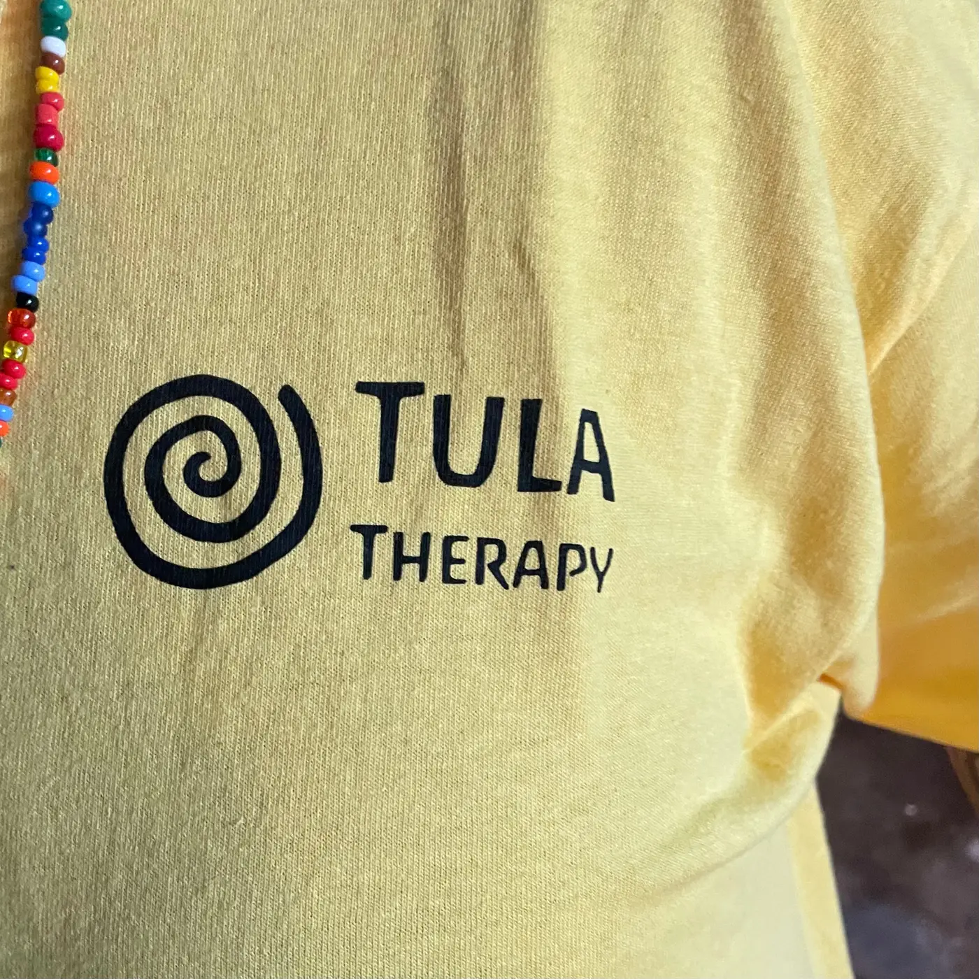 Tula Therapy logo printed on a yellow shirt